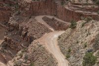 a couple cars driving through the middle of a canyon with a mountain in the back ground