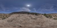 an image of a full moon setting over a desert hill and a tree lined field