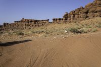 the red rock formations of a rocky area with the dirt covered ground on the opposite side and rock outcrops on the left