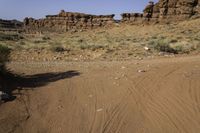 the red rock formations of a rocky area with the dirt covered ground on the opposite side and rock outcrops on the left