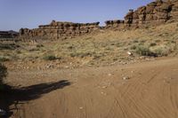 the red rock formations of a rocky area with the dirt covered ground on the opposite side and rock outcrops on the left