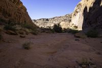 a large rock in a narrow section of sand in the mountains near a river and rocks