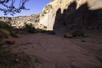 a large rock in a narrow section of sand in the mountains near a river and rocks