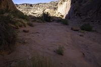 a large rock in a narrow section of sand in the mountains near a river and rocks