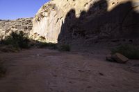 a large rock in a narrow section of sand in the mountains near a river and rocks