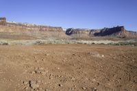 a view of some large rocky mountains in the distance and an area with dirt on it