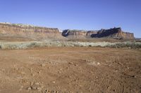 a view of some large rocky mountains in the distance and an area with dirt on it