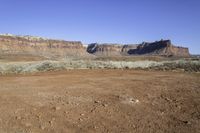 a view of some large rocky mountains in the distance and an area with dirt on it