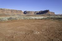 a view of some large rocky mountains in the distance and an area with dirt on it