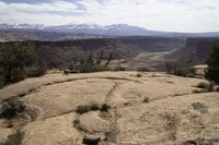 a view of some mountains with hills in the distance from a rocky ledge and valley below