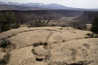 a view of some mountains with hills in the distance from a rocky ledge and valley below