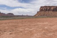 a motorcyclist driving through the desert in front of some mountains and mountains