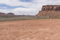 a motorcyclist driving through the desert in front of some mountains and mountains