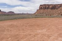 a motorcyclist driving through the desert in front of some mountains and mountains