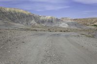 a motorcycle parked on a gravel road near a mountain side landscape with a clear blue sky