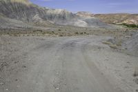 a motorcycle parked on a gravel road near a mountain side landscape with a clear blue sky