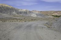 a motorcycle parked on a gravel road near a mountain side landscape with a clear blue sky