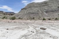 a dirt field filled with rocks in the middle of it and mountains in the background