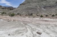 a dirt field filled with rocks in the middle of it and mountains in the background