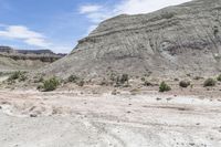 a dirt field filled with rocks in the middle of it and mountains in the background