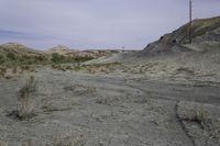 a dirt road in a desert area with no vegetation on the side of it and a wire pole on top