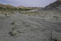 a dirt road in a desert area with no vegetation on the side of it and a wire pole on top