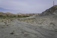 a dirt road in a desert area with no vegetation on the side of it and a wire pole on top