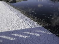 the snow covered surface on the ground by a river and bridge is empty without one person in sight