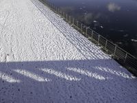 the snow covered surface on the ground by a river and bridge is empty without one person in sight