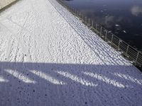 the snow covered surface on the ground by a river and bridge is empty without one person in sight