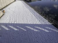 the snow covered surface on the ground by a river and bridge is empty without one person in sight