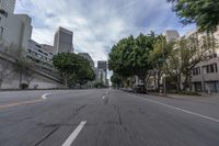 a car is traveling down an empty city street in motion with trees lining the road