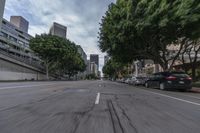 a car is traveling down an empty city street in motion with trees lining the road