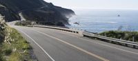 a car driving down a highway that is beside the ocean with a bike on it