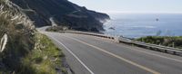 a car driving down a highway that is beside the ocean with a bike on it