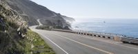 a car driving down a highway that is beside the ocean with a bike on it