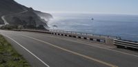 a car driving down a highway that is beside the ocean with a bike on it