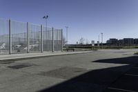 a car is driving past an empty parking lot with a large fenced in area