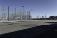 a car is driving past an empty parking lot with a large fenced in area