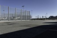 a car is driving past an empty parking lot with a large fenced in area