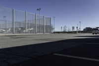 a car is driving past an empty parking lot with a large fenced in area