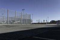 a car is driving past an empty parking lot with a large fenced in area