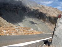 the front end of a car is stopped on a mountainous road as dark clouds loom