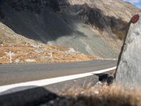 the front end of a car is stopped on a mountainous road as dark clouds loom