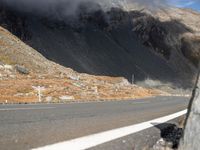 the front end of a car is stopped on a mountainous road as dark clouds loom