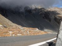 the front end of a car is stopped on a mountainous road as dark clouds loom