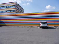 a car parked in front of a multicolored building in a parking lot outside