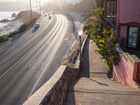 car passing on a beach side road, with light in the background, next to stone stairs