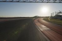 a car on a race track and the sun shining in the background as it passes by
