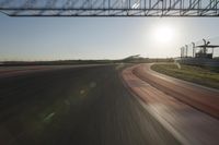 a car on a race track and the sun shining in the background as it passes by